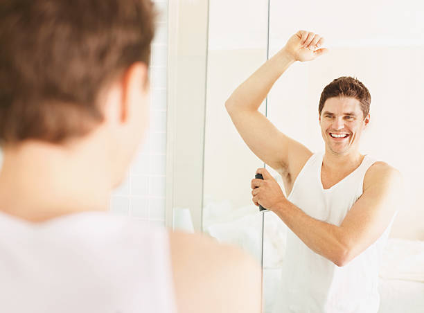istock Happy guy spraying deodorant to underarms 182364063