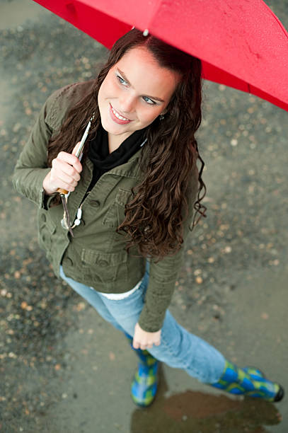young woman with red umbrella on rainy day stock photo