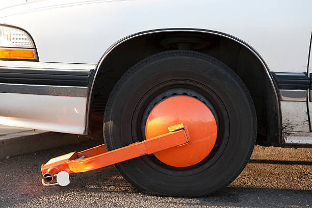 Wheel clamp 2 Wheel clamp on white car. Violated parking limits. car boot stock pictures, royalty-free photos & images