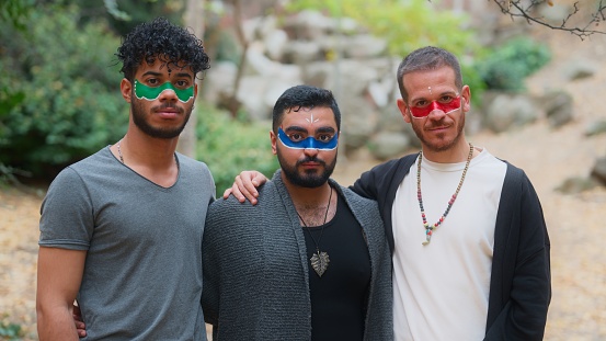 A portrait of group men friends with their faces painted standing side by side in nature. Male friendship concept not lgbtqia concept!
