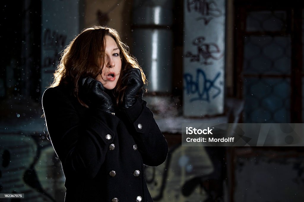 Frozen young woman at night Frozen young woman outdoors portrait in a back street at night. It is snowing Adult Stock Photo
