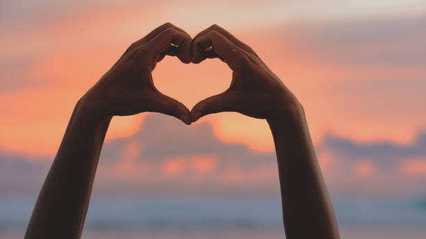 istock Hands forming a heart shape with sunset silhouette 1823673490
