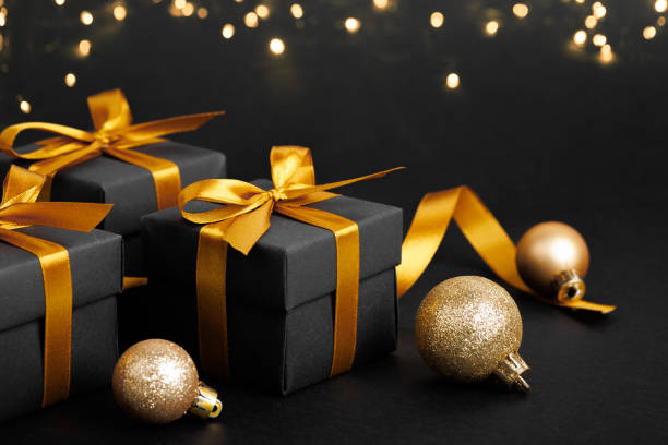 istock Black gift box with golden ribbon bow on black background 1823677210
