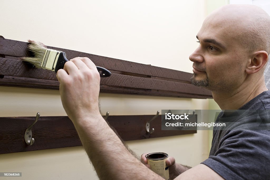 Hombre tinción de madera interior con un pincel - Foto de stock de 30-39 años libre de derechos
