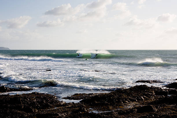 istock Surfers ride a wave at a reef in Porthleven 182368724
