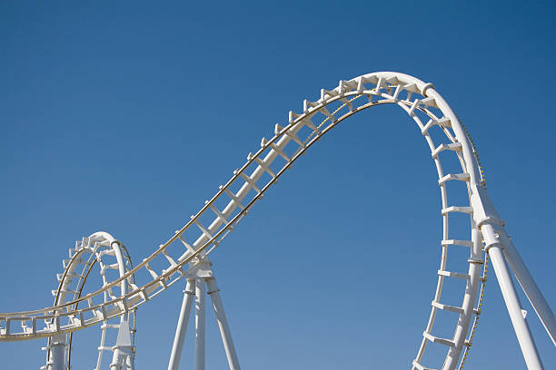 white-achterbahn loops gegen einen blauen himmel - rollercoaster stock-fotos und bilder