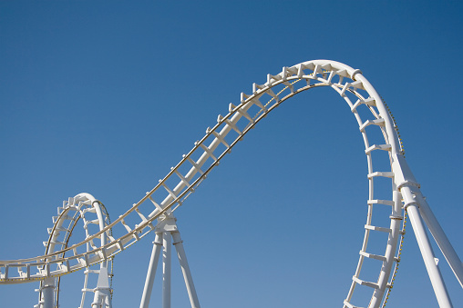 White Rollercoaster Loops Against a Clear Blue Sky
