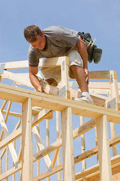 istock Builder Hammering Roof Truss Nail Against Blue Sky 182369523