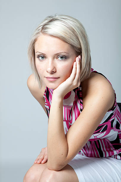 Close-up of a depressed blond woman, looking at camera. Studio shot.