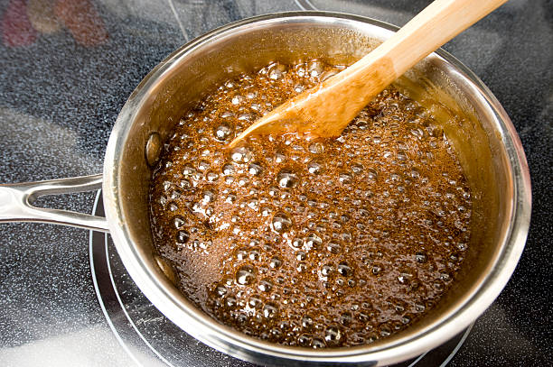 Caramel Sauce bubbles and is stirred on a stove. stock photo