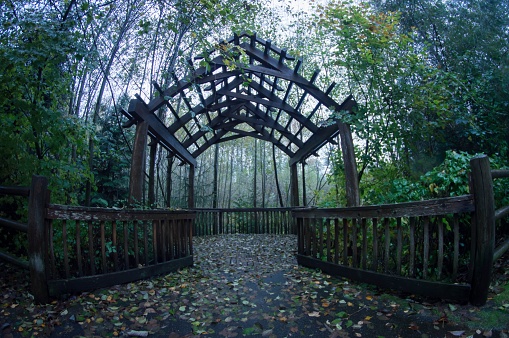 A wooden gazebo with several crosses is situated amongst a tranquil forest setting