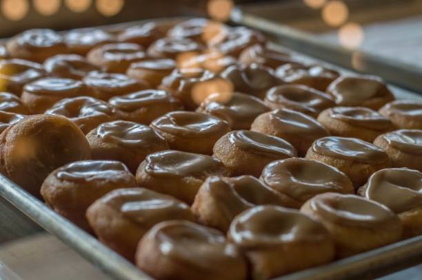 istock Baking pan filled with freshly-baked donuts, each covered in a sweet glaze 1823704694