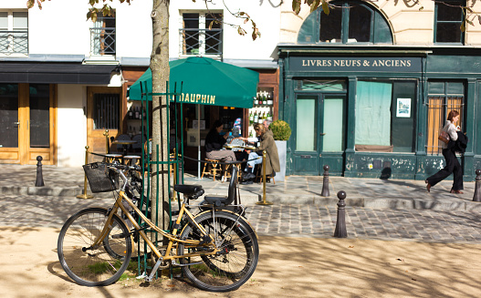 Paris, France: Customers relaxing at a small outdoor cafe on Place Dauphine on Île de la Cité, with bikes in the foreground.