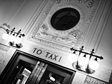 Black and white rendering of TO TAXI directional sign in Seattle train station. Fine grain added.