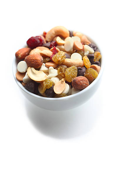Small bowl of trail mix "Small bowl of trail mix, including peanuts, almonts, cashews, dried cranberries, yellow raisins, chocolate chips, white chocolate chips, isolated on white" chocolate white chocolate chocolate chip white stock pictures, royalty-free photos & images
