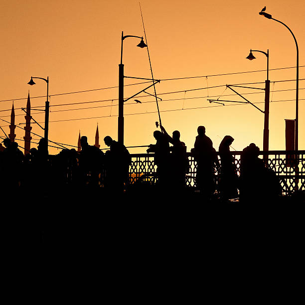 silhouette fisherman at the galata bridge in istanbul, turkey at sunset