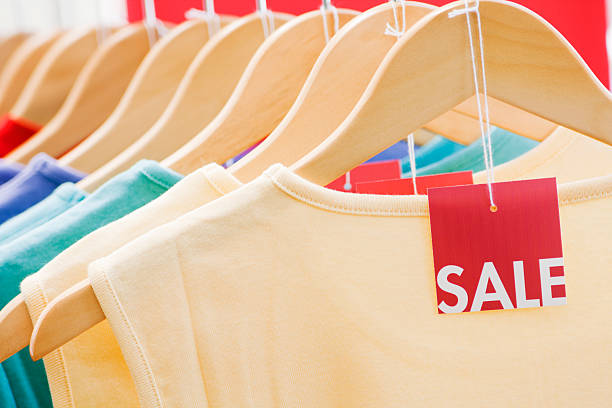 Clothing with Sale Price Tag Label, Fashion Discount Retail Shopping Shirts hanging in a row on hangers, clothing with red sale price tag label for retail fashion discount shopping and bargain hunting. garment store fashion rack stock pictures, royalty-free photos & images