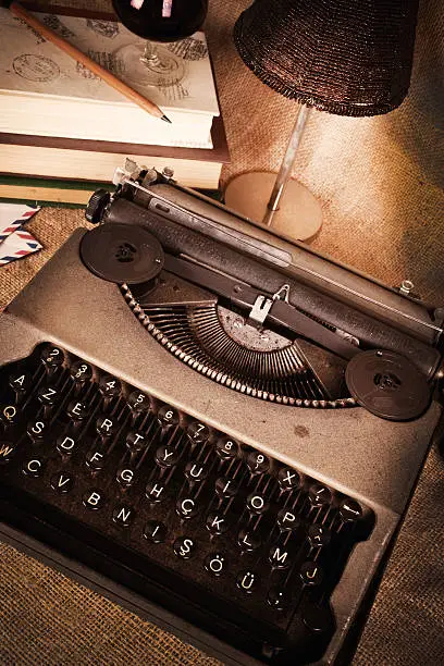Photo of A vintage type writer on a wooden desk with moody lighting