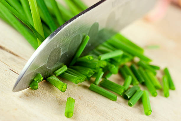 Knife cutting chives "A knife is cutting chives; very narrow depth of field, focus on first couple of chives.see related:" chive photos stock pictures, royalty-free photos & images