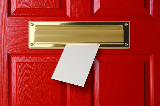 A mail slot in a red door.