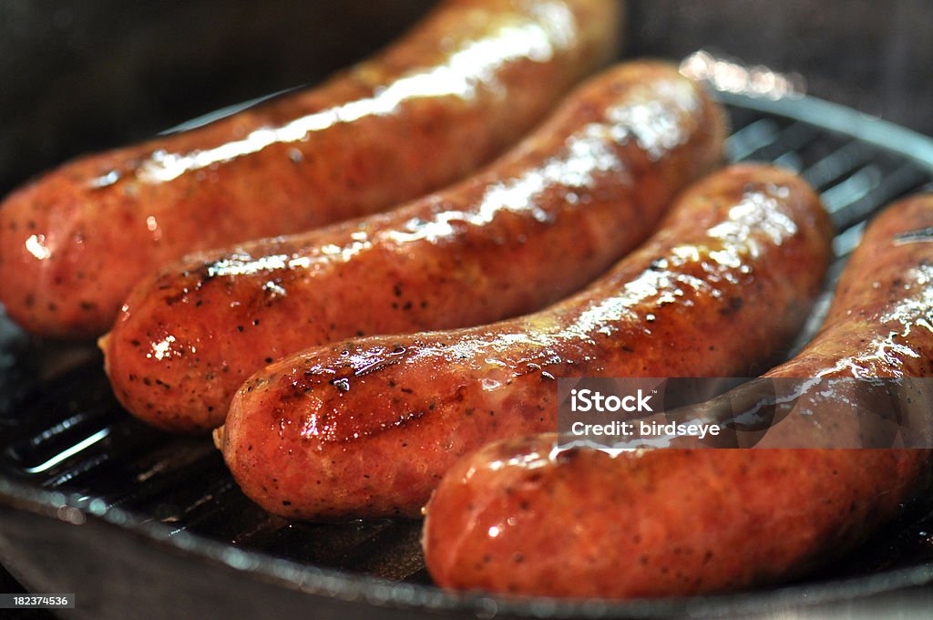 Sausages! Four large sausages cooking in a cast iron skillet. Sausage Stock Photo