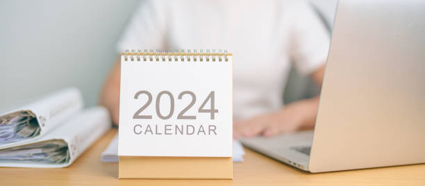 2024 Year Calendar on table with business woman using laptop computer. countdown, Happy New Year, Resolution, Goals, Plan,  Action, Mission and financial Concept