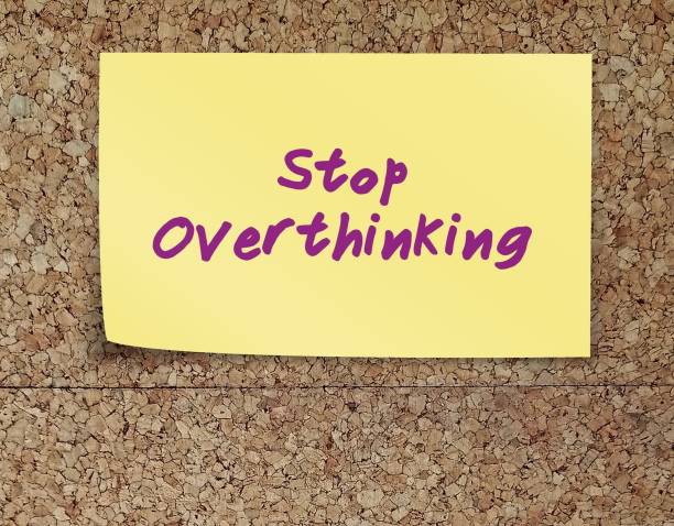 Stick note on copy space cork board with handwritten text STOP OVERTHINKING, to remind self to stop thinking too much which lead to stress and anxiety - break free from negative thoughts pattern pegar una nota en un tablero de corcho con texto escrito a mano deja de pensar demasiado, para recordarte a ti mismo que debes dejar de pensar demasiado, lo que conduce al estrés y la ansiedad: libérate del patrón de pensamientos negativos