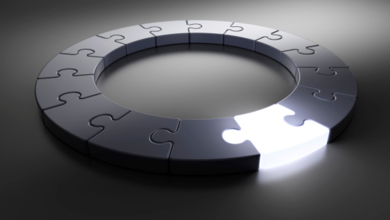 Royalty-free image of a circle of puzzle pieces with one glowing.