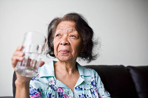 Senior black woman holding a glass of water stock photo