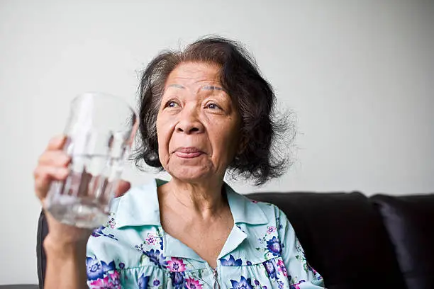 Photo of Senior black woman holding a glass of water