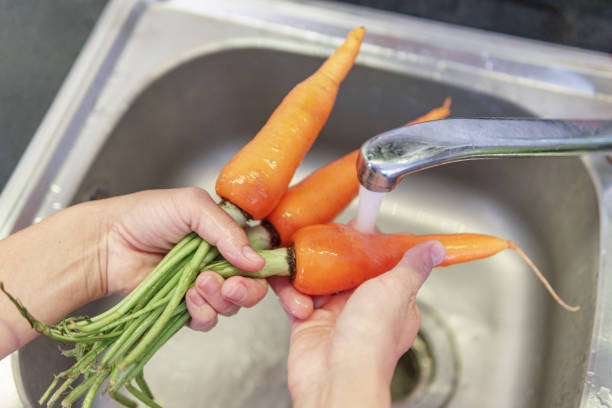 istock Woman hands washing fresh orange carrots in a kitchen 1823780232