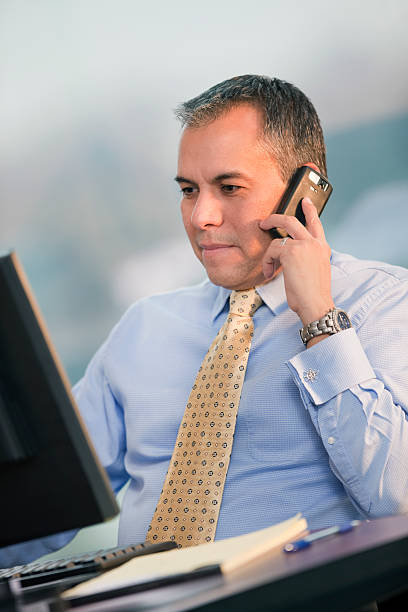 istock Hispanic Business Man On Cellphone Looking At Computer 182378963