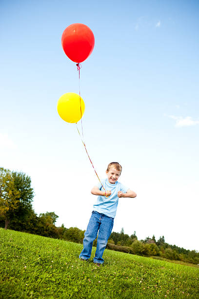 istock Happy Young Boy Holding Balloons Outside 182379592