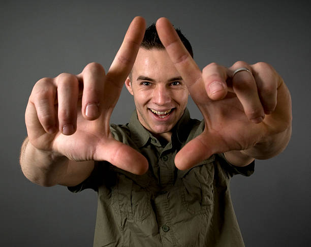 Imagination A man is focusing through a frame made by his fingers. determination focus the bigger picture human hand stock pictures, royalty-free photos & images