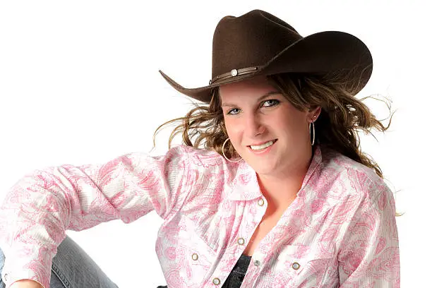 "A cowgirl posing with blue jeans, cowboy boots and cowboy hat."