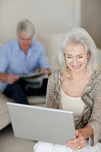 istock Senior woman using laptop with husband at the back 182381297
