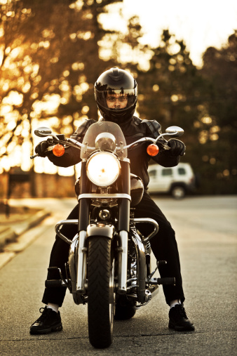 Motorcyclist riding a classic cruiser styled bike at dusk.