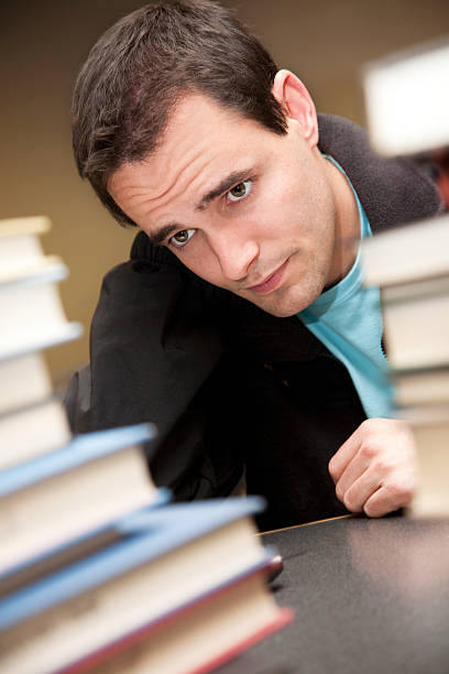 istock Worried College Student Looking at His Library School Books 182381659