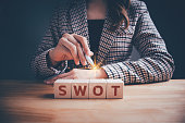 Businesswoman with SWOT text on wooden cube block. Swot analysis strategy for business plan and growth, Teamwork brainstorming vision and goal, evaluate work, planning technique operations concept.