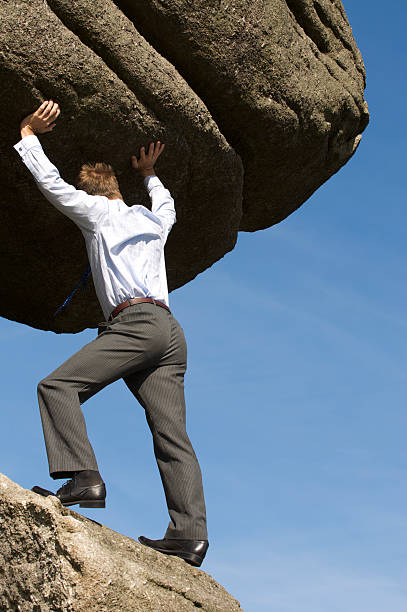 potente empresario empujando boulder de vida - pushing over burdened rock men fotografías e imágenes de stock