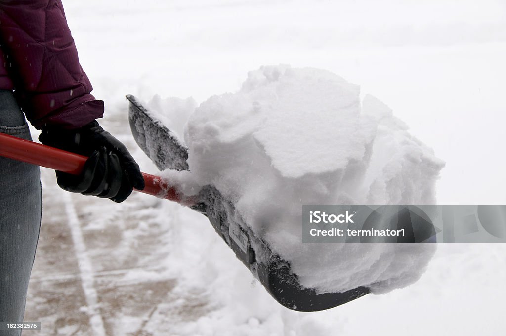 保持の雪をシャベルで取り除く - 雪かきスコップのロ��イヤリティフリーストックフォト