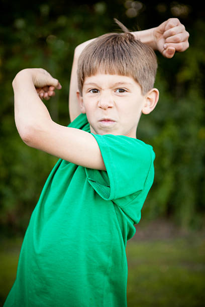 istock Tough Young Boy Flexing His Muscles Outside 182383000