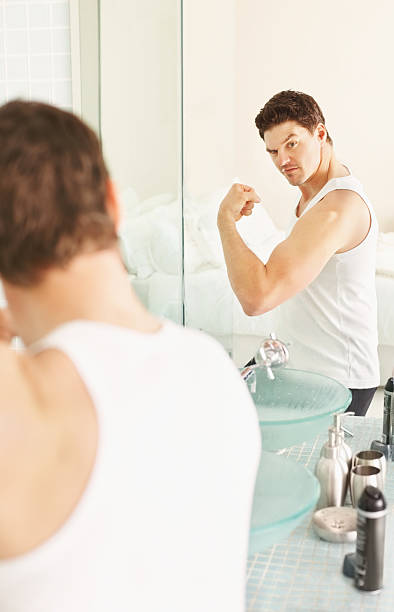 istock Guy looking at his muscles in mirror 182383180