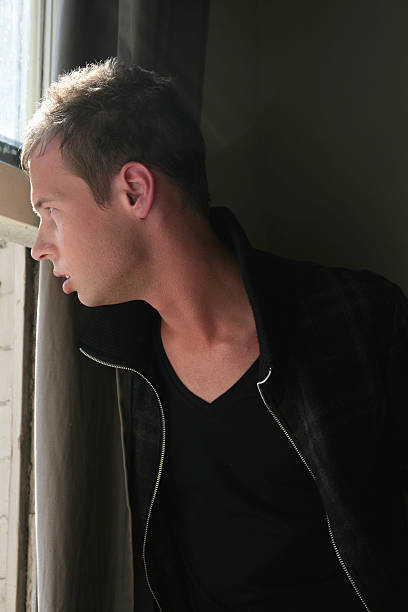 istock Male model profile looking out window in thought 182383595