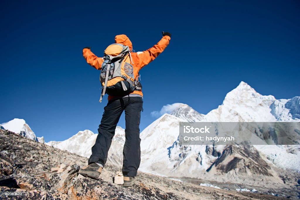 Mujer ascensores sus brazos en la victoria, el monte Everest en el fondo - Foto de stock de Adulto libre de derechos
