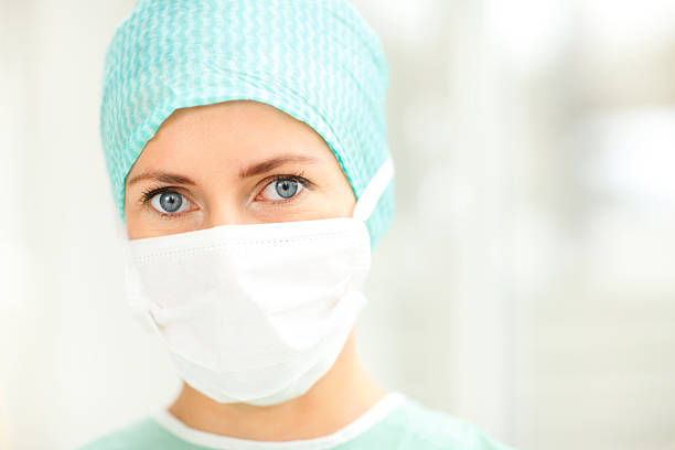 Portrait of mid adult doctor at hospital. Female surgeon is standing in emergency room. She is wearing protective scrubs.