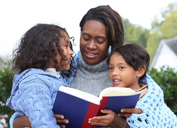 istock Mom with her kids reading a book. 182385577