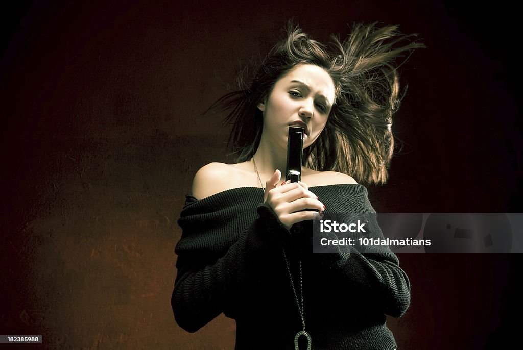 Dangerous Lady Attractive female with flying hair holding a gun Activity Stock Photo