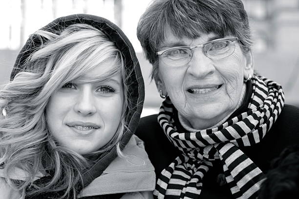 Grandmother and Granddaughter A grandmother and her granddaughter sit outside together on a winter's day. grandmother real people front view head and shoulders stock pictures, royalty-free photos & images