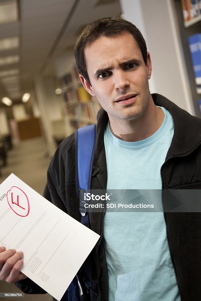 Upset College Student in Library Holding F Grade on Exam Upset College Student in Library Holding F Grade on Exam.See more from this series: 20-24 Years Stock Photo
